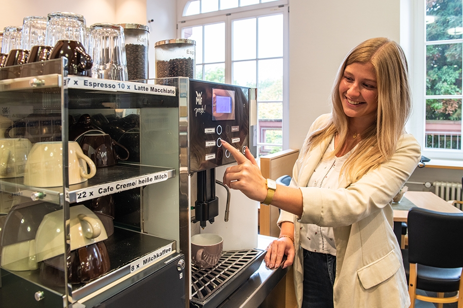 Eine Frau bedient eine Kaffeemaschine in der Cafeteria. Eine Frau bedient eine Kaffeemaschine in der Cafeteria.