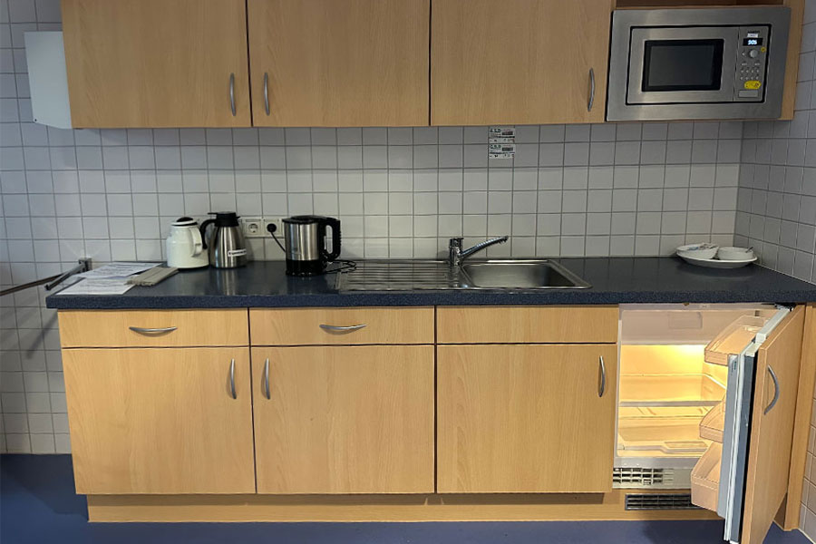 Eine Küchenzeile mit Kühlschrank, Mikrowelle und Wasserkocher. Eine Küchenzeile mit Kühlschrank, Mikrowelle und Wasserkocher.