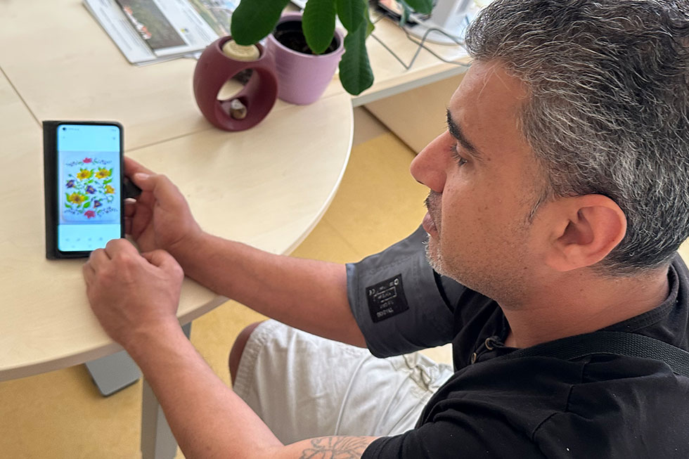 Fadel Temsah zeigt an seinem Mobiltelefon Fotos von seinen Kunstwerken Fadel Temsah zeigt an seinem Mobiltelefon Fotos von seinen Kunstwerken